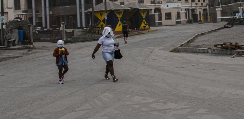 Una mujer y una niña caminan por una calle cubierta de ceniza provocada por la erupción del volcán La Soufrière, en Kingstown. | AP