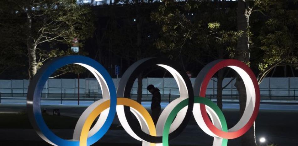 En esta foto del 24 de marzo de 2020, un individuo camina cerca de los anillos olímpicos cerca del Estadio Nacional de Tokio.