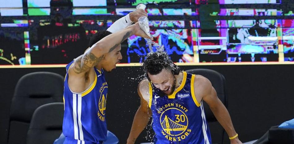 El jugador de los Warriors de Golden State Juan Toscano-Anderson (izquierda) arroja agua sobre su compañero Stephen Curry (30) tras la victoria de su equipo sobre los Nuggets de Denver, en San Francisco. (AP Foto/Jeff Chiu)