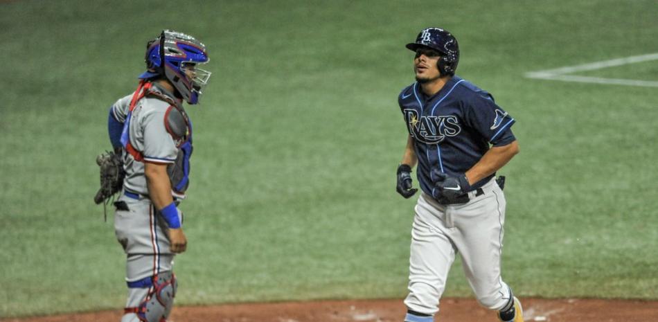 El receptor de los Texas Rangers, José Treviño, observa cómo Willy Adames de los Tampa Bay Rays, a la derecha, anota en un jonrón solitario de los Rangers Taylor Hearn durante la octava entrada de un juego de béisbol este lunes 12 de abril de 2021 en St. Petersburg, Florida.