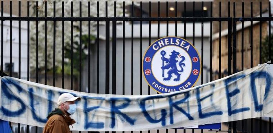 Un peatón pasa junto a una pancarta anti-europea de la Superliga que dice "Supergreed" (Súper Avaricia) afuera de una entrada al estadio de fútbol Stamford Bridge en Londres el 20 de abril de 2021. Foto: Adrian Dennis/AFP.