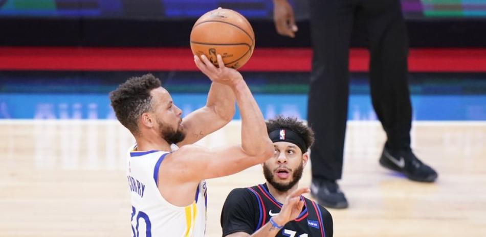 El base de los Warriors de Golden State Stephen Curry lanza el balón mientras lo defiende Seth Curry de los 76ers de Filadelfia. (AP Photo/Matt Slocum)