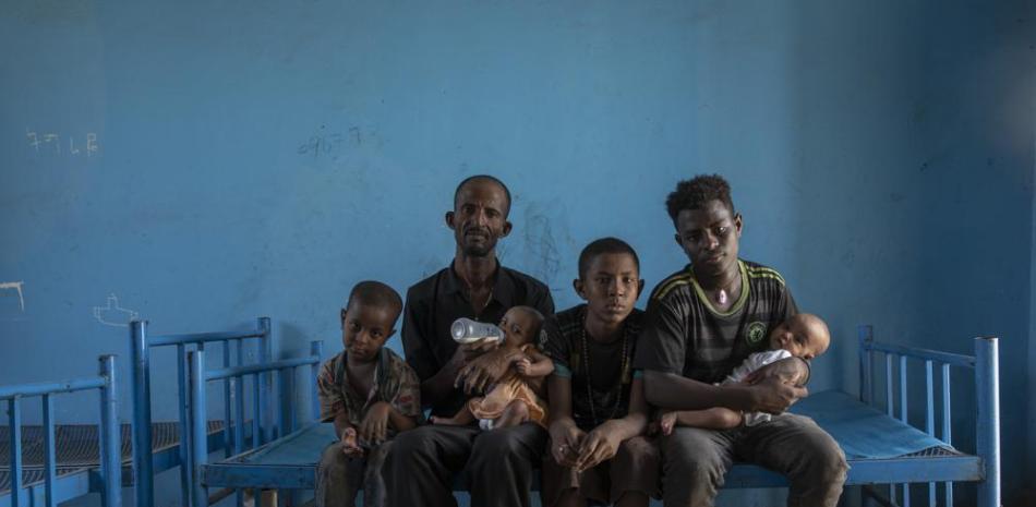 Abraha Kinfe Gebremariam (segundo por la izquierda), un refugiado de Tigray de 40 años, posa para una fotografía con sus hijos Micheale (izquierda), de 5 años, y Daniel (centro), de 11; su cuñado Goytom Tsegay (segundo por la derecha), de 19 años, y sus gemelas de 4 meses, Aden (derecha) y Turfu Gebremariam (en sus brazos), dentro del albergue donde vive la familia en Hamdayet, en el este de Sudán, cerca de la frontera con Etiopía, el 23 de marzo de 2021. Otra refugiada, Mulu Gebrencheal, madre de cinco hijos, se ha convertido en su asesora, ofreciéndole consejos para el cuidado de los bebés. Abraha y sus hijos aprenden rápido, añadió lamentando la muerte de la madre. (AP Foto/Nariman El-Mofty)