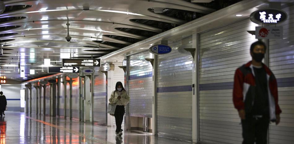 Unas personas caminan por una zona de comercios en el subterráneo cerrados debido a la emergencia por el coronavirus en Osaka, Japón, el 25 de abril de 2021.

Foto: Yohei Fukuyama/Kyodo News via AP