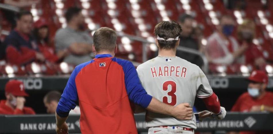 Bryce Harper, de los Filis de Filadelfia, abandona el encuentro con ayuda, tras ser impactado en el rostro por un pitcheo. (AP Foto/Joe Puetz)