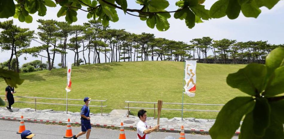Un corredor relevista lleva la antorcha olímpica en Nago, prefectura de Okinawa, Japón, sábado 1 de mayo de 2021. El relevo de la antorcha olímpica tendrá un nuevo desvío este fin de semana con la cancelación de un tramo en la isla de Miyakojima debido a un brote de coronavirus.