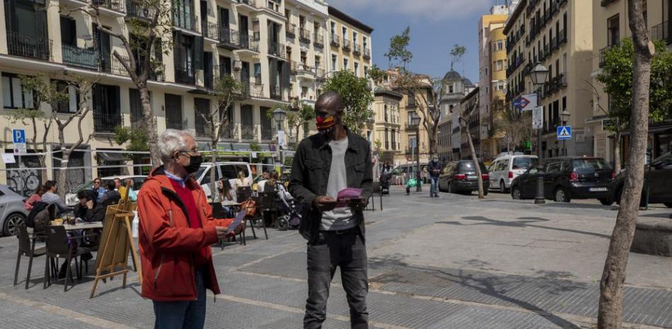Serigne Mbaye, que se presenta dentro de la lista del partido antiausteridad Unidas Podemos en las elecciones regionales de Madrid, habla con un posible votante durante un acto electoral en Madrid, España, el viernes 16 de abril de 2021. (AP Foto/Bernat Armangue)