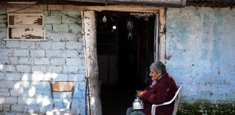 Una anciana descansa fuera de su casa en el barrio Puerta de Hierro, en el municipio de La Matanza, provincia de Buenos Aires. Foto AFP.