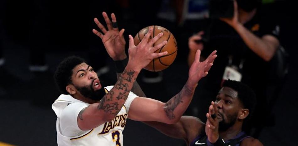 Anthony Davis, de los Lakers, atrapa un rebote defensivo frente a Deandre Ayton, de los Suns, en acción del partido en el baloncesto de la NBA.