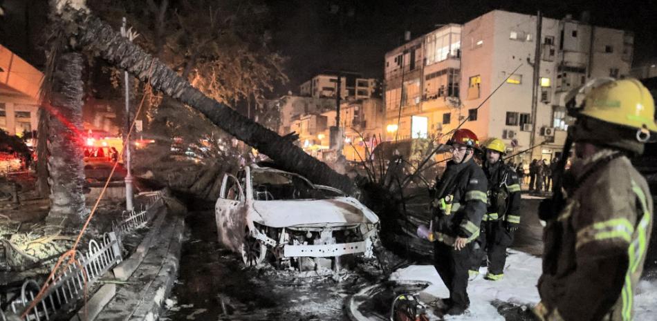 Los bomberos israelíes pasan junto a vehículos quemados apagados en Holon cerca de Tel Aviv, el 11 de mayo de 2021, después de que se lanzaran cohetes hacia Israel desde la Franja de Gaza controlada por el movimiento palestino Hamas. Ahmad Gharabli / AFP