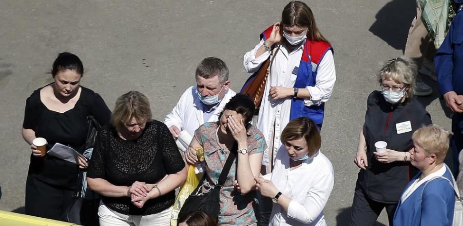 Médicos y amigos ayudan a una mujer a subir a una ambulancia en una escuela después de un tiroteo en Kazán, Rusia, el martes 11 de mayo de 2021. Los medios rusos informan que varias personas murieron y cuatro resultaron heridas en un tiroteo en una escuela en la ciudad de Kazán. (Foto AP / Roman Kruchinin)