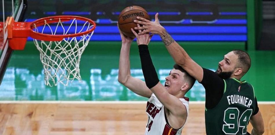 Evan Fournier, de los Celtics, trata de bloquear un intento al canasto de Tyler Herro, de los Heat, en acción del martes por la noche en la NBA.