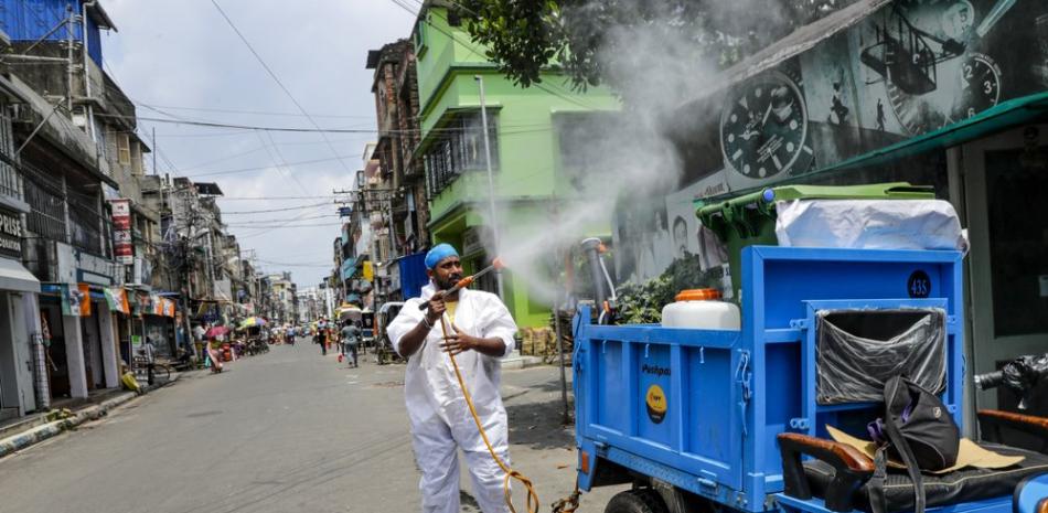 Un trabajador cívico rocía desinfectantes frente a una tienda mientras una mujer con mascarilla pasa por su lado en Calcuta, India, el domingo 30 de agosto de 2020.

Foto: AP / Bikas Das