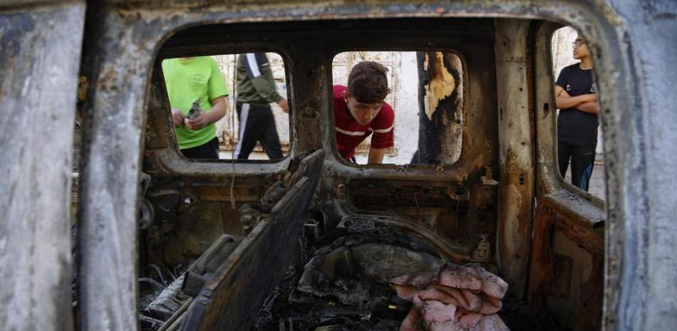 Niños palestinos miran a un auto destruido en un ataque aéreo israelí, en Ciudad de Gaza, el miércoles 19 de mayo de 2021. (AP Foto/Hatem Moussa)