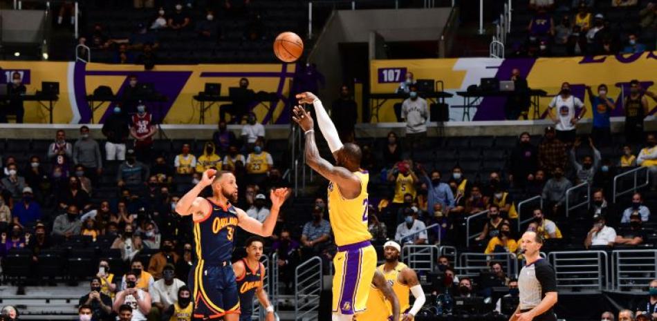 LeBron James, de los Lakers, se eleva para anotar el canasto decisivo sobre la defensa de Stephen Curry, de los Warriors, en el partido de repesca en el baloncesto de la NBA.