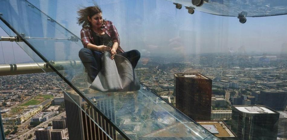 En esta fotografía de archivo del 23 de junio de 2016, un miembro de los medios de comunicación se desliza por un tobogán de vidrio durante una vista previa en el edificio US Bank Tower en el centro de Los Ángeles. (Foto AP / Richard Vogel, Archivo)