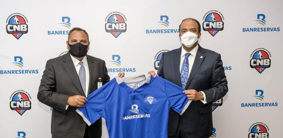 Junior Noboa entrega al administrador general de Banreservas, Samuel Pereyra, el uniforme que llevarán los equipos de Pequeñas Ligas.
