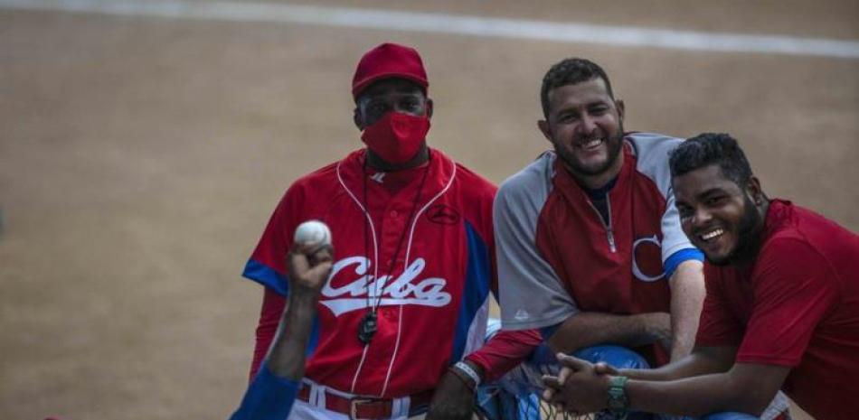 Yoanni Yera Montalvo (izquierda) hace un lanzamiento durante una práctica de la selección cubana, mientras varios de sus compañeros sonríen, en La Habana.