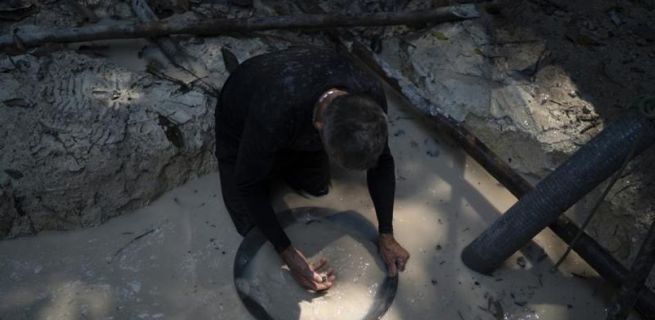 un minero utiliza un recipiente para separar fragmentos de oro de la tierra con agua en una mina ilegal en la selva amazónica, en la zona de Itaituba, estado de Pará, en Brasil. (AP Foto/Lucas Dumphreys, Archivo)