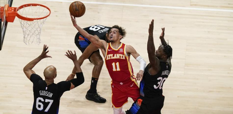Trae Young (11) de los Atlanta Hawks dispara contra Julius Randle (30) y Taj Gibson (67) de los New York Knicks durante el Juego 3 de la serie de playoffs de primera ronda de baloncesto de la NBA este en Atlanta.