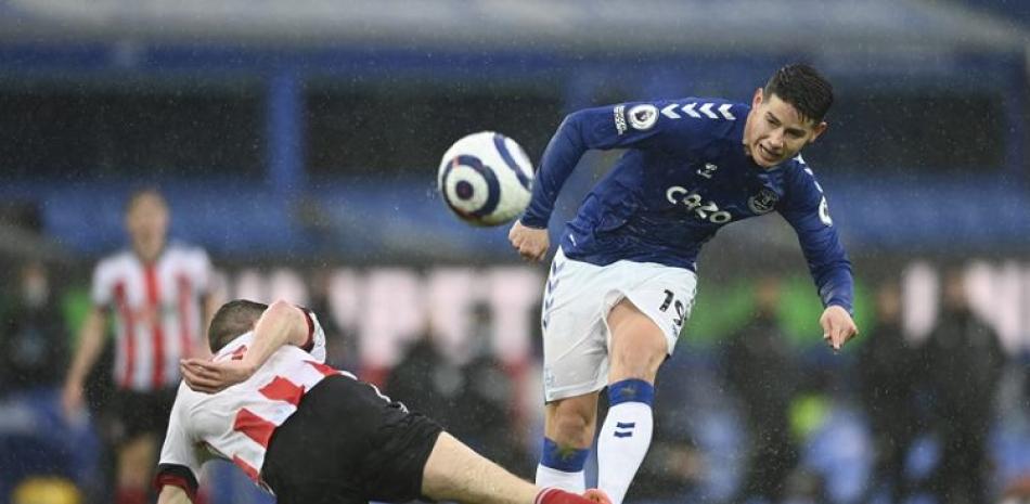 James Rodriguez, derecha, del Everton, realiza un remate ante la barrida de Chris Basham, del Sheffield United, en partido de la Liga Premier.
