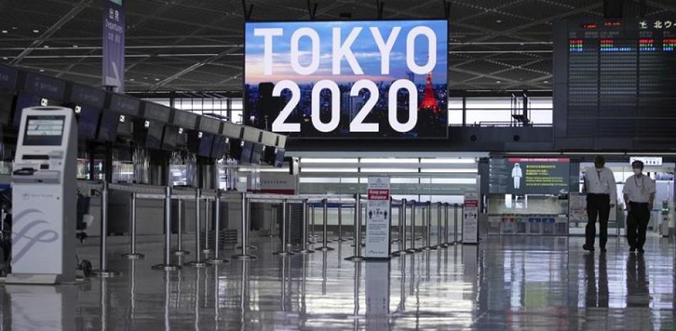 Personal, con mascarilla para protegerse del coronavirus, pasean por una zona de embarque vacía en el aeropuerto internacional de Narita.