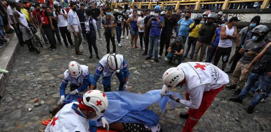 Paramédicos recogen el cuerpo de un hombre asesinado por manifestantes antigubernamentales al que acusaron de matar a un compañero manifestante que bloqueaba su paso en un control de carretera establecido por manifestantes en Cali, Colombia, el viernes 28 de mayo de 2021. (AP Foto/Andrés Gonzalez)
