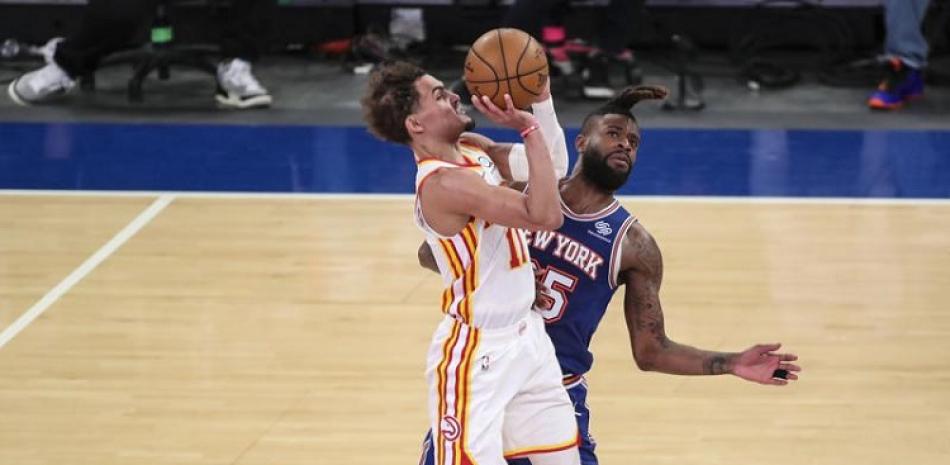Trae Young, de Atlanta, lanza un triple mientras lo defiende Reggie Bullock, de los Knicks, en el juego 5 de la serie de primera ronda.