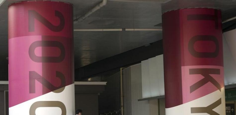 Un individuo se inclina en un pilar con publicidad de los Juegos Olímpicos de Tokio 2020.