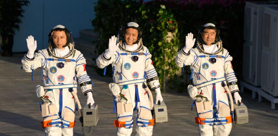 Los astronautas chinos (de izquierda a derecha), Tang Hongbo, Nie Haisheng y Liu Boming saludan mientras se preparan para embarcar en un ascensor que les llevará a su cápsula espacial ayer en el Centro de Lanzamiento de Satétiles Jiuquan, en Jiuquan, en el noroeste de China. AP