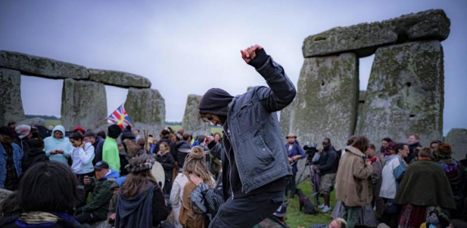 Un grupo de personas permanece en el interior del círculo de piedras durante el solsticio de verano en Stonehenge, donde algunos saltaron la valla para ingresar al área y ver el amanecer del día más largo del año en el Reino Unido, en Amesbury, Inglaterra, el lunes 21 de junio de 2021. (Ben Birchall/PA vía AP)