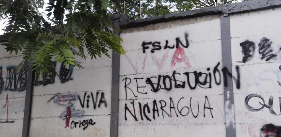 Una pared pintada con graffitis con un mensaje que alguna vez decía en español: "Resiste Nicaragua", fue pintado por otro que ahora dice "Viva la revolución" en Managua, Nicaragua, el jueves 17 de junio de 2021. Recientemente el gobierno del presidente Daniel Ortega detuvo a 13 líderes de la oposición, incluidos cuatro aspirantes a la presidencia para las elecciones del 7 de noviembre. (AP Foto/Miguel Andrés)