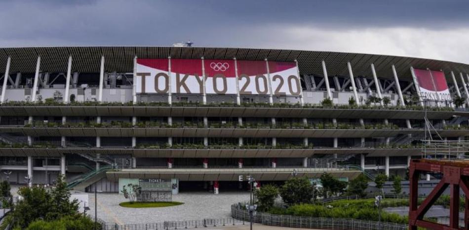 Un empleado camina frente al Estadio Nacional de Tokio, el miércoles 23 de junio de 2021, sede de las ceremonias de los Juegos Olímpicos de Tokio 2020.