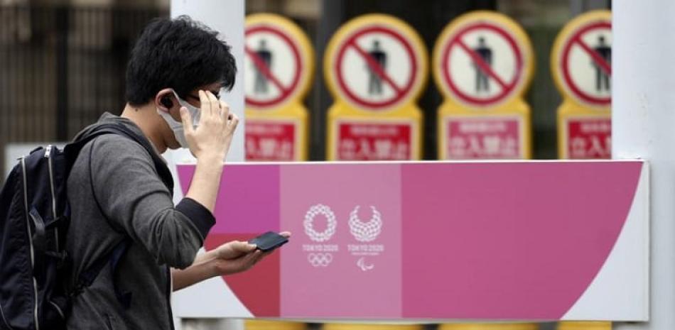 Un hombre, con mascarilla para frenar la propagación del coronavirus, pasa junto a un anuncio de los Juegos Olímpicos y Paralímpicos de Tokio 2020, en Tokio.