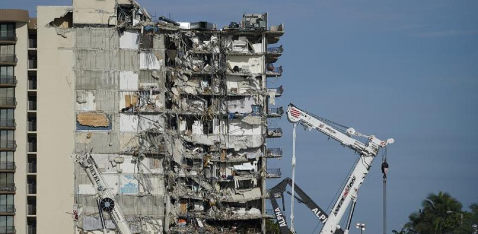 Trabajadores contemplan la pila de escombros del edificio residencial parcialmente derruido Champlain Towers South en Surfside, Florida, jueves 1 de julio de 2021. Las autoridades suspendieron las labores de búsqueda y rescate el jueves por temores sobre la estabilidad de la estructura. (AP Foto/Mark Humphrey)