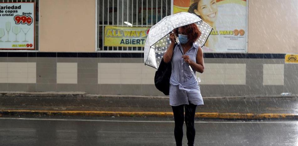 Una mujer usa sombrilla mientras cruza una calle en San Juan (Puerto Rico). EFE/Thais Llorca/Archivo