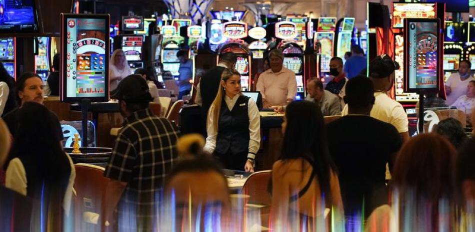 En imagen del 24 de junio de 2021, varias personas recorren la zona del casino durante la noche de apertura del Resorts World Las Vegas, en Las Vegas. (AP Foto/John Locher)
