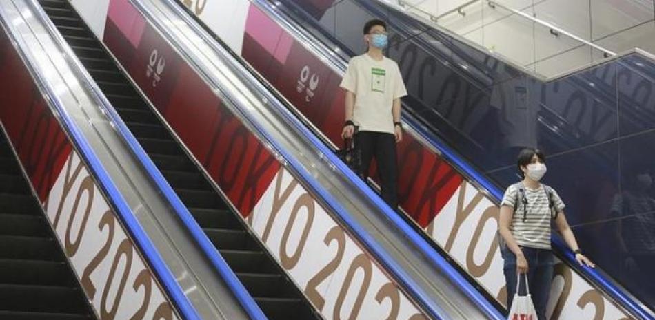 Un par de personas con mascarillas baja por elevador con banderas con el logo de los Juegos Olímpicos en Tokio, el pasado 7 de junio.
