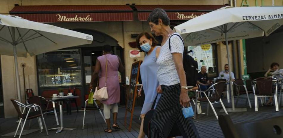 Dos mujeres caminan cerca de un bar en Pamplona, norte de España, el 5 de julio de 2021. (AP Foto/Alvaro Barrientos)