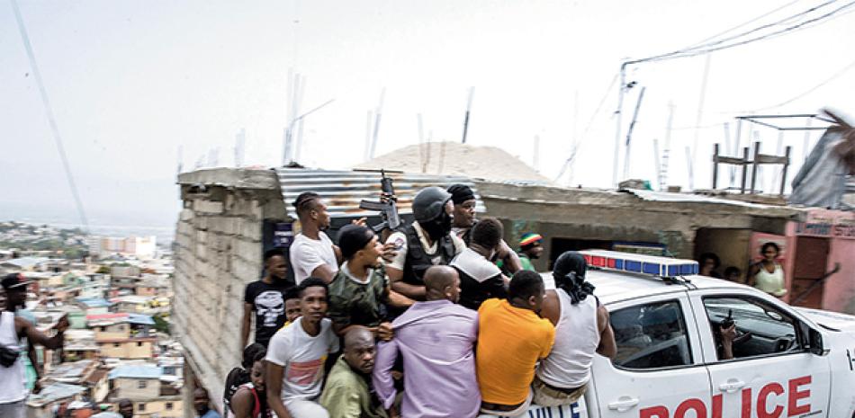 Una camioneta policial llena de civiles y policías recorre el municipio de Jalousie, donde arrestaron a hombres acusados de haber asesinado al presidente Moise. AFP