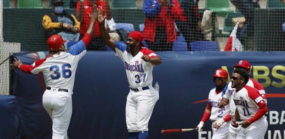 Johan Mieses, de República Dominicana, es felicitado por sus compañeros después de que anotó contra Venezuela durante un partido clasificatorio al béisbol de los Juegos Olímpicos.