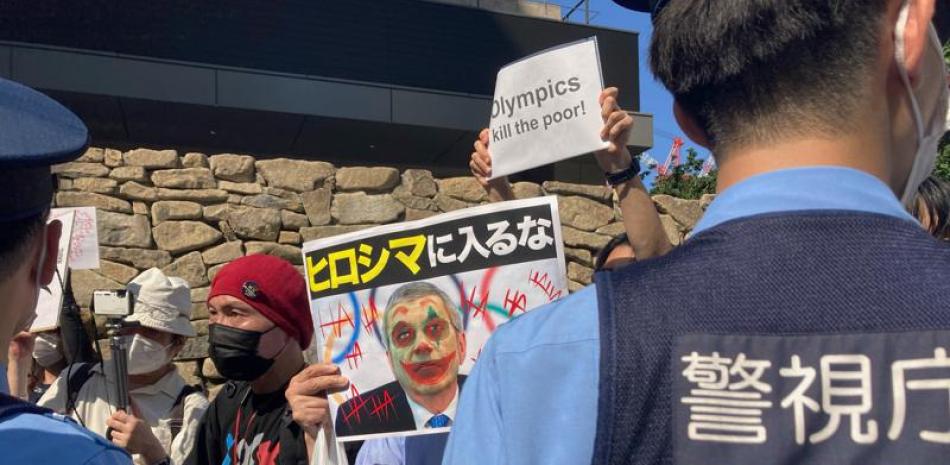 Manifestantes contra los Juegos Olímpicos y Paralímpicos de Tokio 2020 enfrentan a la policía en Tokio, sábado 10 de julio de 2021. El cartel en el centro muestra la leyenda "no entren a Hiroshima" y la foto del presidente del COI, Thomas Bach, quien prevé visitar la ciudad antes de los juegos. (AP Foto/Kwiyeon Ha)