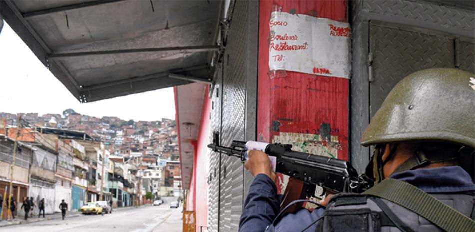 Un miembro de la Policía Nacional Bolivariana apunta a un posible objetivo en el barrio Cota 905. AFP