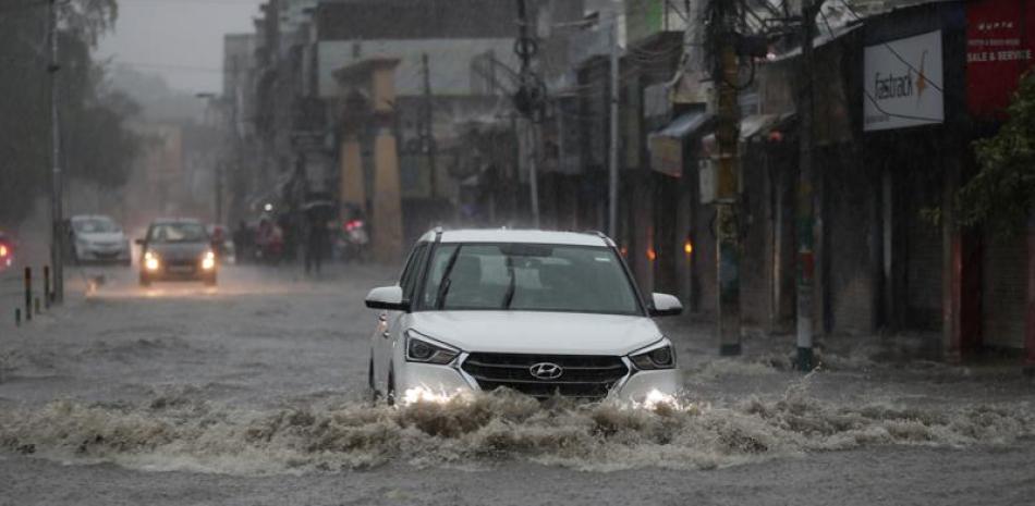 Un auto pasa por una calle inundada durante las lluvias del monzón en Jammu, India, el lunes 12 de julio de 2021. (AP Foto/Channi Anand)