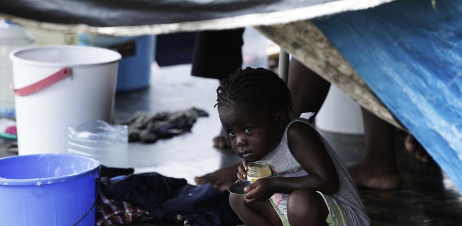 Un niño migrante se asoma debajo de una carpa en un campamento de migrantes en medio de la nueva pandemia de coronavirus, en Lajas Blancas, provincia de Darién, Panamá, el sábado 29 de agosto de 2020.

Foto: AP/Arnulfo Franco
