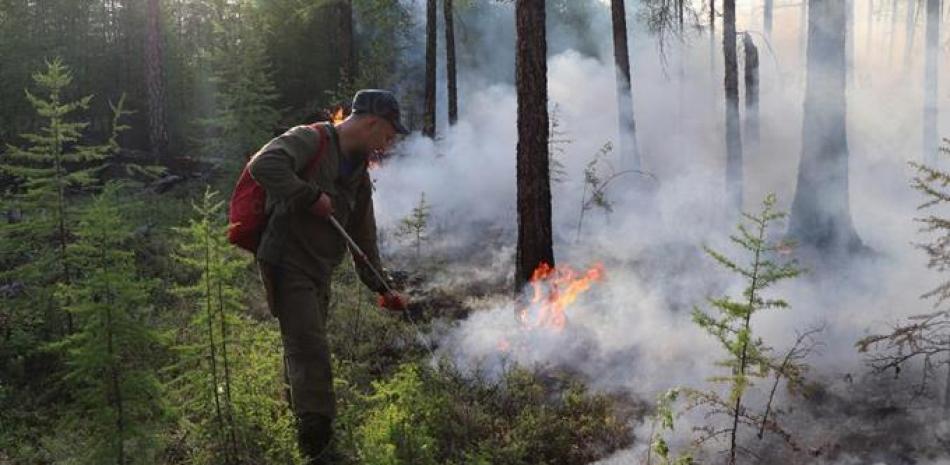 En esta fotografía proporcionada por el servicio de prensa del Ministerio de Emergencias de Rusia, un bombero combate un incendio forestal en la región de Yakutia, en Rusia, el miércoles 14 de julio de 2021. (Servicio de prensa del Ministerio de Emergencias de Rusia vía AP)