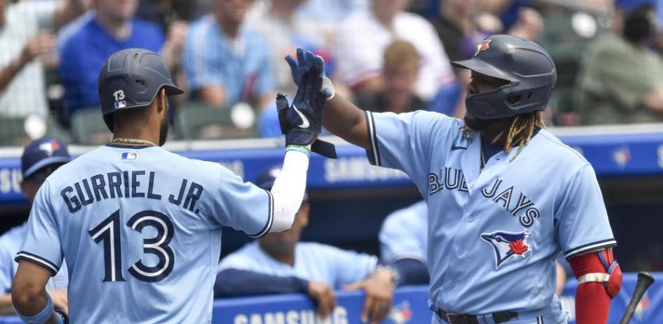 Toronto Blue Jays' Lourdes Gurriel Jr. (13) is congratulated by Vladimir Guerrero Jr. after scoring against the Texas Rangers on a ground out by Marcus Semien during the third inning of the first baseball game of a doubleheader in Buffalo, N.Y., Sunday, July 18, 2021. (AP Photo/Adrian Kraus)