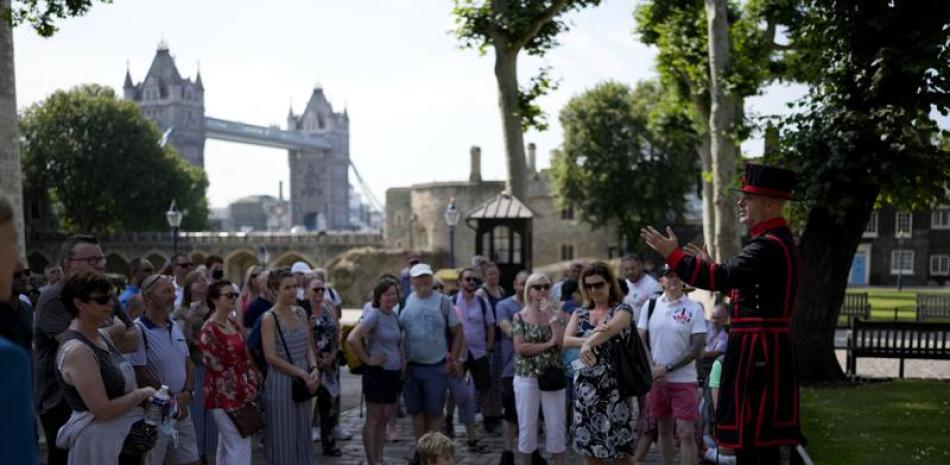 Un grupo de visitantes escuchan a un guía en la Torre de Londres el lunes 19 de julio de 2021, la primera visita luego de 16 meses de estar cerrada debido a la pandemia de coronavirus. (AP Foto/Matt Dunham)