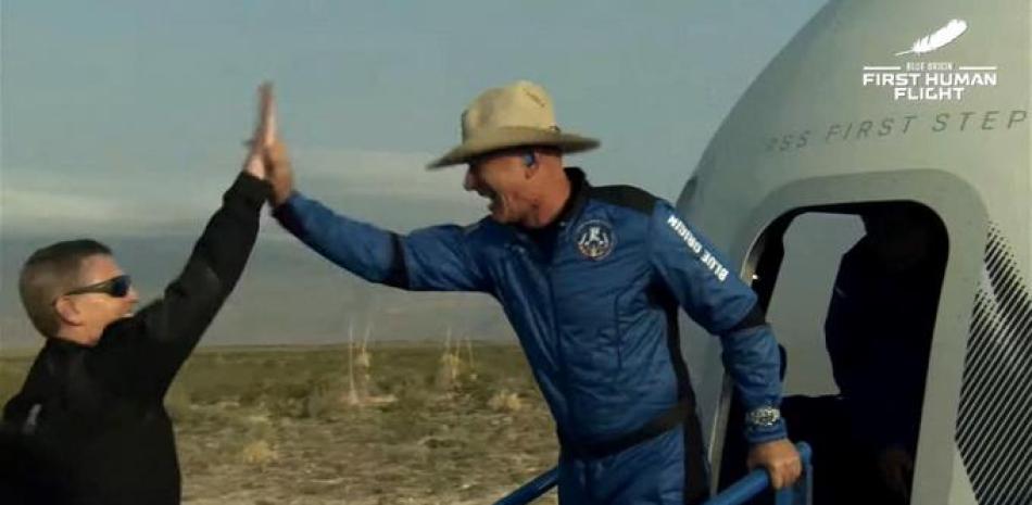 Esta imagen fija tomada del video de Blue Origin muestra a Jeff Bezos (derecha) celebrando después de salir de la cápsula reutilizable New Shepard de Blue Origin que regresó del espacio y aterrizó de manera segura el 20 de julio de 2021 en Van Horn, Texas. La primera misión con tripulación de Blue Origin es un vuelo de 11 minutos desde el oeste de Texas a una altitud de 106 km (65 millas), y viceversa, para coincidir con el 52 aniversario del primer aterrizaje en la Luna.
Folleto / ORIGEN AZUL / AFP