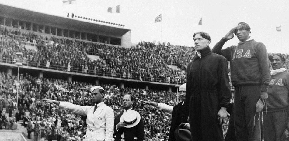 El medallista de oro Jesse Owens, segundo desde la derecha, saluda mientras se escucha el himno de Estados Unidos tras los 100 metros en los Juegos Olímpicos de Berlín.